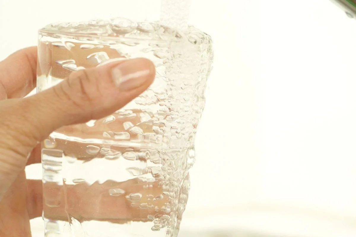 Un verre se remplit au robinet — la qualité sanitaire de l'eau se contrôle et se compare